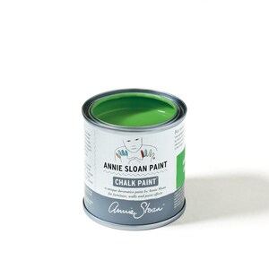 May include: A small, open can of Annie Sloan Chalk Paint in a vibrant green color. The can is silver with a white label featuring the brand name, a child's drawing, and the words "CHALK PAINT". The paint is designed for furniture, walls, and paint effects.