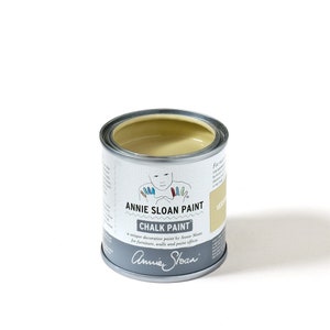 May include: A can of Annie Sloan Chalk Paint in the color Versailles. The paint is a light yellow color and the can has a white label with the Annie Sloan logo and the words "Chalk Paint" and "Versailles".