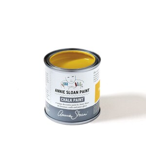 May include: A yellow can of Annie Sloan Chalk Paint. The can has a label with the Annie Sloan logo and the text "Chalk Paint" and "a unique decorative paint by Annie Sloan for furniture, walls and paint effects".