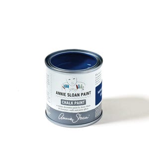 May include: A small, open can of Annie Sloan Chalk Paint in a deep blue color. The can has a white label with the brand name and product details. The paint is designed for furniture, walls, and paint effects.
