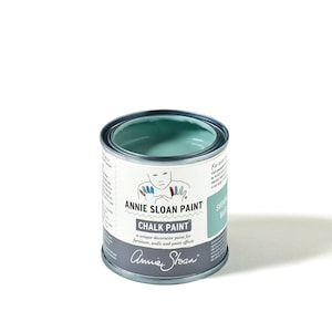 May include: An open can of Annie Sloan Chalk Paint in Swedish Blue. The paint is a light teal color. The can has a white label with the brand name and product information. The can is made of metal and has a silver rim.