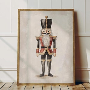 Może przedstawiać: Aquarela przedstawiająca tradycyjnego żołnierza-łamacza orzechów. Łamacz orzechów jest ubrany w czerwony i złoty mundur z czarnym kapeluszem i białą brodą. Tło jest jasnobeżowe.