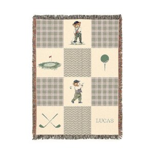 May include: A beige and green golf-themed throw blanket with a plaid pattern and fringe trim. The blanket features illustrations of a bear playing golf, a golf course, golf ball on a tee, and crossed golf clubs. The name "LUCAS" is printed on the blanket.
