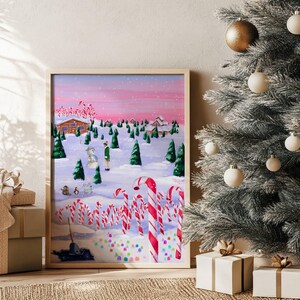 May include: A framed painting of a winter scene with candy canes, a snowman, and a person in a green coat. The artwork has a pink and purple sky, with a Christmas tree and wrapped gifts in the foreground. The painting is in a wooden frame.