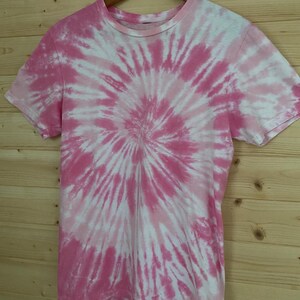 May include: Pink and white tie-dye t-shirt with a spiral pattern.