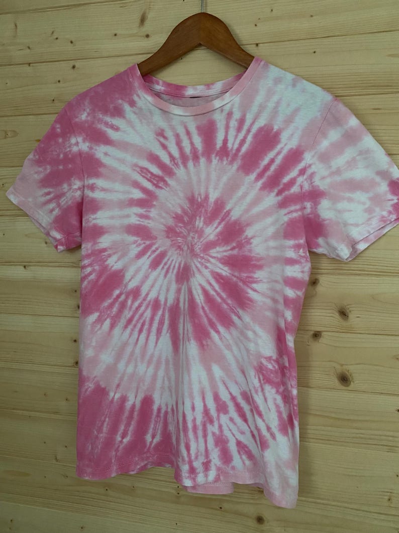 May include: Pink and white tie-dye t-shirt with a spiral pattern.