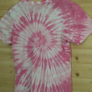 May include: Pink and white tie-dye t-shirt with a spiral pattern.