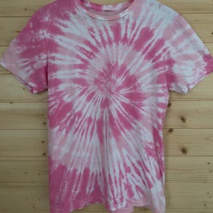 May include: Pink and white tie-dye t-shirt with a spiral pattern.