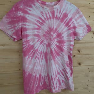 May include: Pink and white tie-dye t-shirt with a spiral pattern.