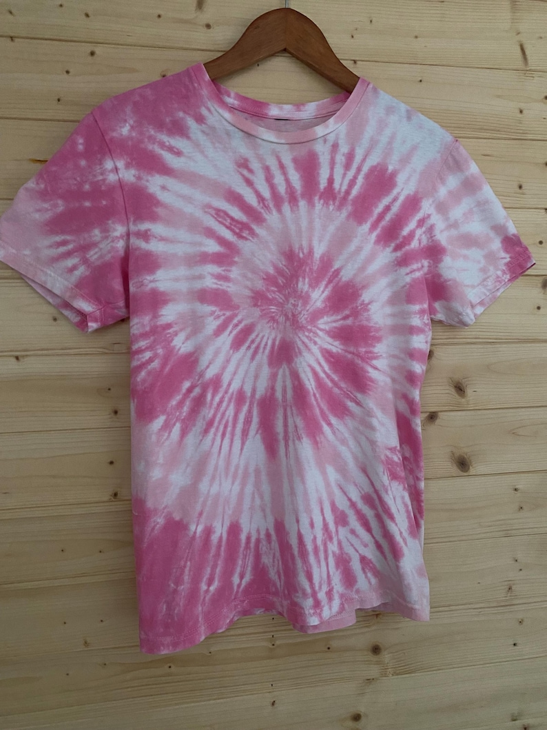 May include: Pink and white tie-dye t-shirt with a spiral pattern.