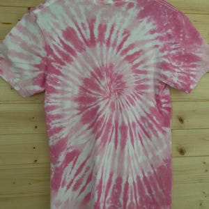 May include: Pink and white tie-dye t-shirt with a spiral pattern.
