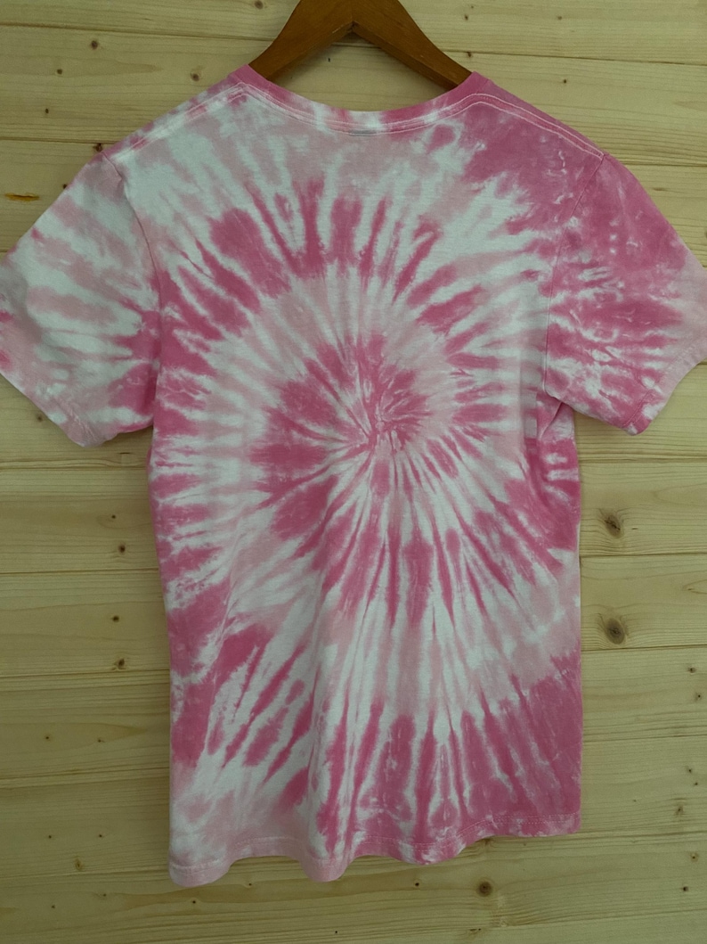 May include: Pink and white tie-dye t-shirt with a spiral pattern.