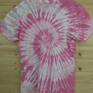 May include: Pink and white tie-dye t-shirt with a spiral pattern.