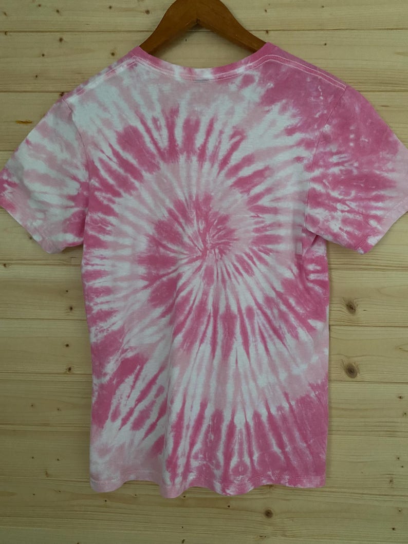 May include: Pink and white tie-dye t-shirt with a spiral pattern.