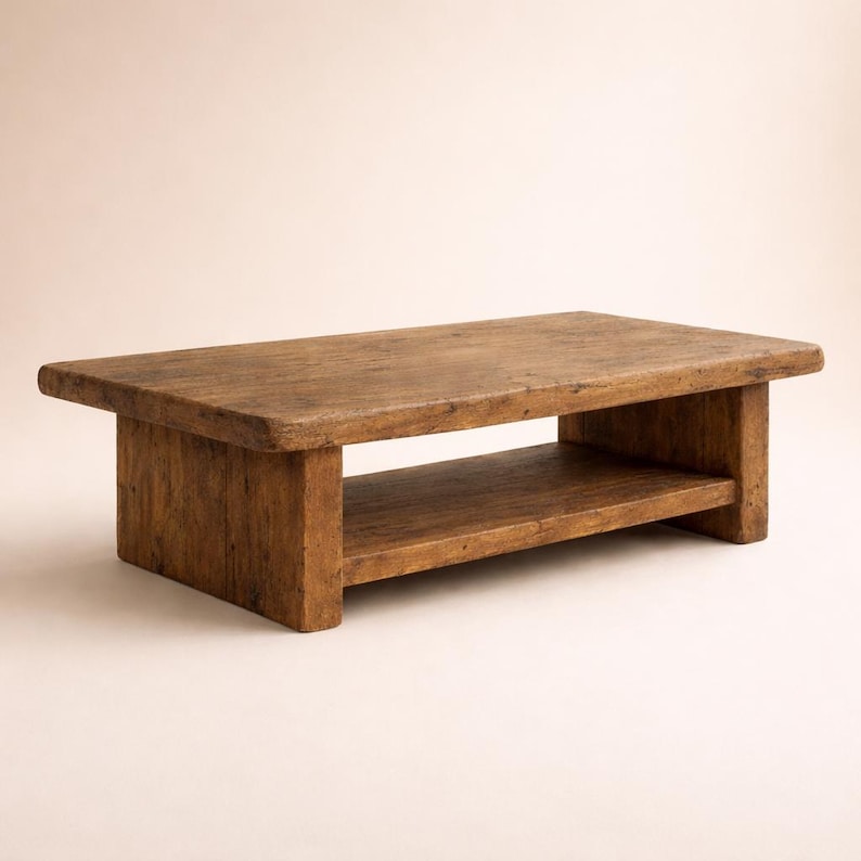 May include: A rectangular, low-profile coffee table made of weathered, light brown wood. The table features a lower shelf for storage and has a rustic, aged appearance. The table is approximately 48 inches long, 24 inches wide, and 16 inches high.