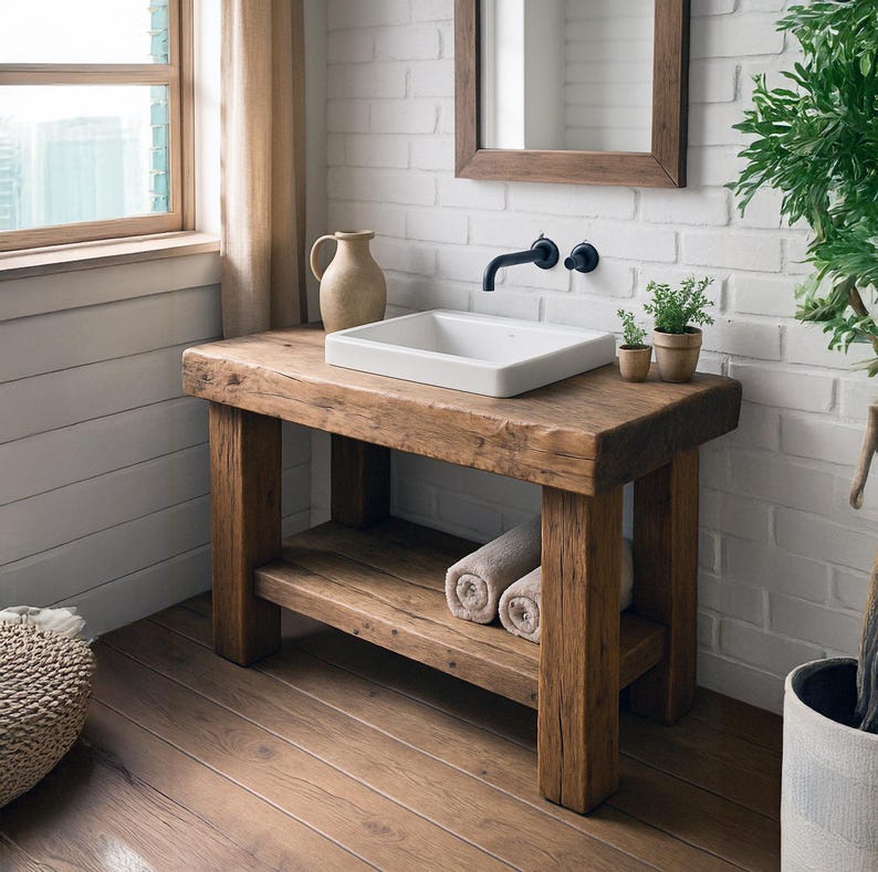 May include: A rustic wooden vanity with a white rectangular sink, set against a white brick wall. The vanity has a lower shelf with rolled towels. A mirror and faucet are mounted above the sink, with small potted plants adding a touch of greenery.