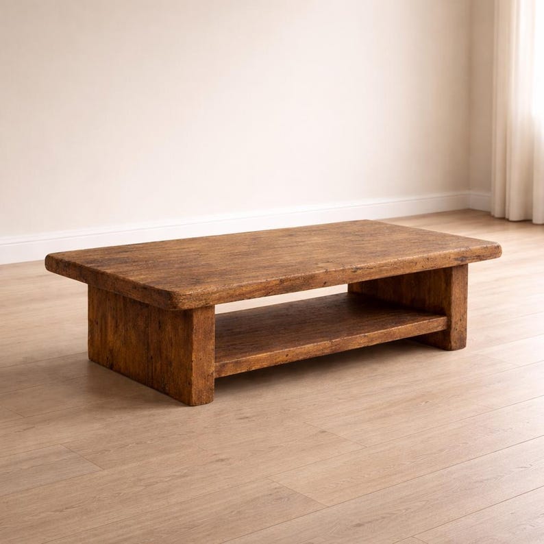 May include: A rectangular, rustic coffee table made of weathered wood. The table has a lower shelf for storage and is finished in a warm, natural brown tone. The table is approximately 48 inches long, 24 inches wide, and 16 inches high.