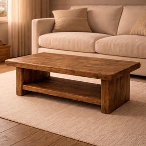 May include: A rectangular, low-profile wooden coffee table with a lower shelf. The table is made of a warm-toned wood and has a rustic, natural appearance. The table is approximately 48 inches long, 24 inches wide, and 16 inches high.