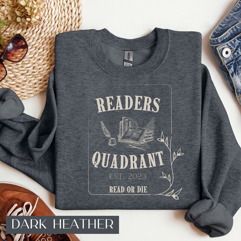 May include: Dark heather grey sweatshirt with a vintage-style graphic that reads "Readers Quadrant Est. 2023 Read or Die". The graphic features a quill pen, an inkwell, and a stack of books.