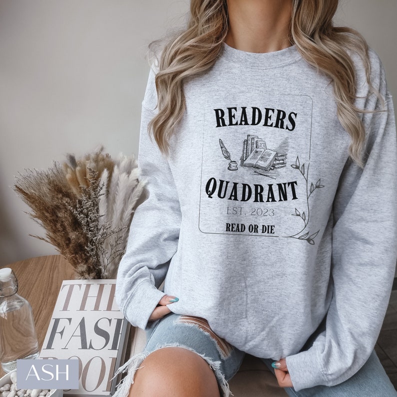 May include: A grey sweatshirt with a black graphic design that says "Readers Quadrant Est. 2023 Read or Die". The graphic includes a drawing of a quill pen and a stack of books.