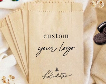 May include: A stack of brown paper bags with a custom logo and the text "custom your logo" and "happy holidays" with a small pine tree graphic.