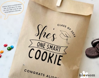 Könnte beinhalten: Braune Papiertüte mit einem Abschluss-Thema. Die Tüte hat eine schwarz-weiße Grafik mit dem Text "She's One Smart Cookie" mit einer Abschluss-Kappe und dem Text "Class of 2024". Die Tüte hat auch den Text "Congrats Alison!" und ein kleines Logo mit dem Text "Blossom Paperie Shop".