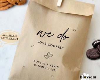 May include: A brown paper bag with the text "we do LOVE COOKIES" printed on it. The bag also has the text "ROSLYN & KEVIN OCTOBER 7, 2023" printed on it. The bag is decorated with small stars and hearts. The text "AVAILABLE IN WHITE & KRAFT" is printed on a white speech bubble.