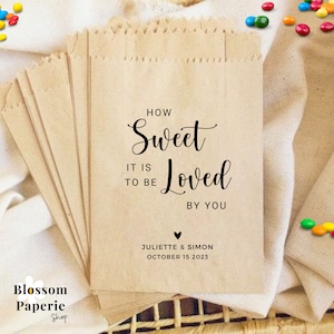 May include: Brown paper bags with a wedding favour message that reads "How Sweet It Is To Be Loved By You" with the couple's names and wedding date below.