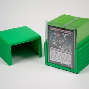 Op de afbeelding: Groene plastic kaarthouder met een kaartspel erin. De bovenste kaart is een Magic: The Gathering-kaart met Ink-Eyes, Servant of Oni.