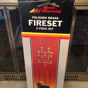 May include: A box for a 5-piece polished brass fireplace tool set. The box is red, yellow, and black with the words "House Warming" and "Fireset" in white. The set includes a poker, tongs, shovel, brush, and stand.