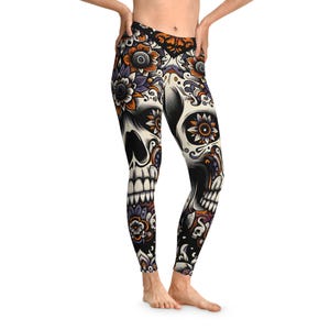 Peut inclure: Legging noir avec un motif de tête de mort mexicaine. La tête de mort est ornée de motifs floraux orange, violets et blancs. Le legging est taille haute et moulant.