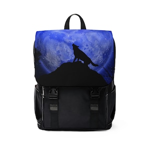 May include: Black backpack with a striking design of a howling wolf silhouette set against a blue night sky and full moon. It has a flap closure with two black buckles and a top handle.