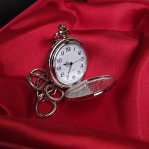 A silver pocket watch with a photo taken on a red background. Personalized picture or photo printed pocket watch