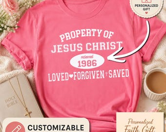 May include: A pink t-shirt with white text that reads "PROPERTY OF JESUS CHRIST" and "LOVED FORGIVEN+SAVED". The year "1986" is in an oval. The shirt is customizable. A "Personalized Gift" tag is also visible.