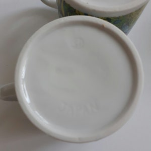 May include: White ceramic mug with a colorful floral design and the word "JAPAN" printed on the bottom.