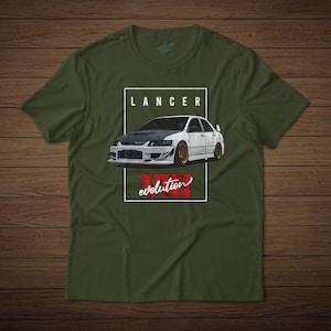 May include: A green t-shirt with a white Mitsubishi Lancer Evolution VII printed on the front. The car is white with a black hood and black racing stripes. The text "LANCER" is printed above the car and "evolution" is printed below the car.