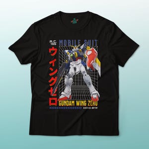 May include: Black t-shirt featuring a colorful illustration of a Gundam Wing Zero mobile suit. The design includes Japanese text and the words "MOBILE SUIT" and "GUNDAM WING ZERU". The graphic is set against a grid background.