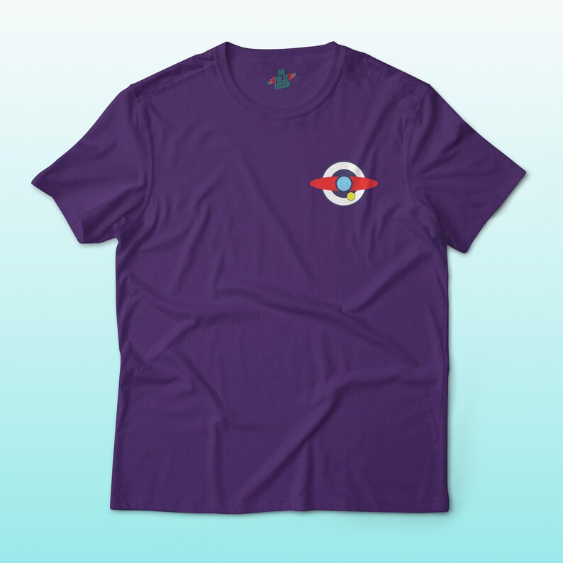 Puede incluir: Una camiseta morada con un peque&ntilde;o gr&aacute;fico de un dise&ntilde;o rojo, blanco y azul. El gr&aacute;fico es una representaci&oacute;n estilizada de un planeta o cuerpo celeste. La camiseta tiene mangas cortas y cuello redondo.