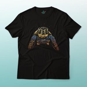 May include: Black t-shirt featuring a detailed illustration of a sea turtle. The turtle design showcases a blend of colors, including blue, orange, and yellow, creating a vibrant and eye-catching graphic. The shirt is a classic crew neck style.