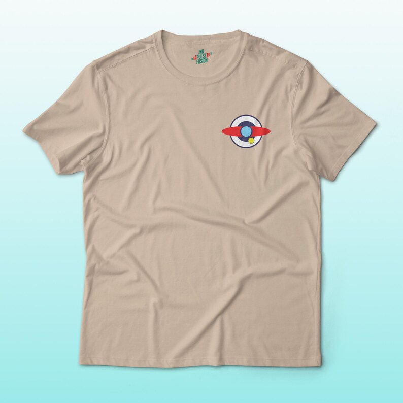 Puede incluir: Una camiseta de color beige con un peque&ntilde;o gr&aacute;fico colorido en el pecho. El gr&aacute;fico representa un dise&ntilde;o rojo, blanco y azul con un acento amarillo. La camiseta tiene mangas cortas y cuello redondo.