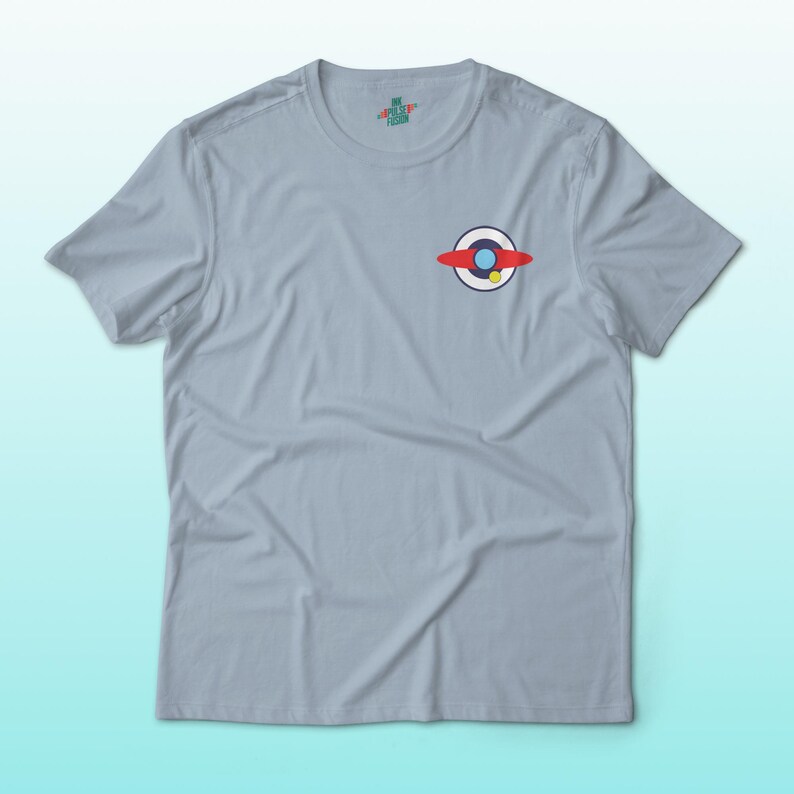 Puede incluir: Camiseta azul claro con un peque&ntilde;o gr&aacute;fico en el pecho. El gr&aacute;fico presenta un dise&ntilde;o rojo, blanco y azul con un acento amarillo. La camiseta tiene mangas cortas y cuello redondo.