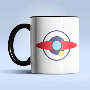 Puede incluir: Taza de cer&aacute;mica blanca con asa y borde negros. La taza presenta un gr&aacute;fico colorido de un dise&ntilde;o rojo, azul y amarillo que se asemeja a un planeta o nave espacial. El dise&ntilde;o est&aacute; centrado en la superficie de la taza.
