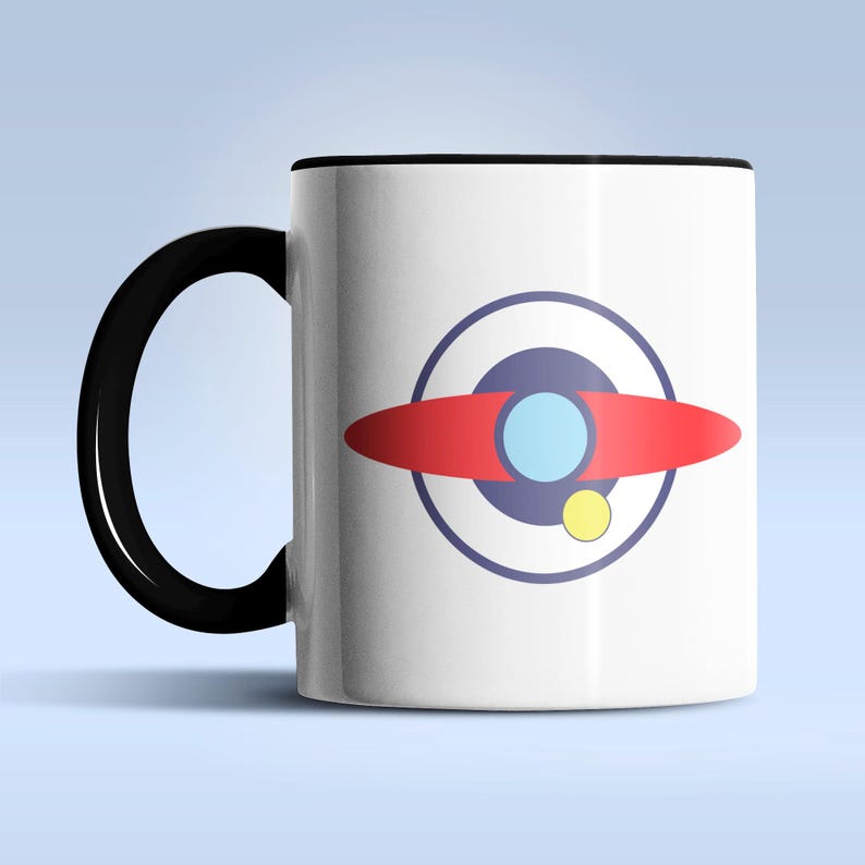 Puede incluir: Taza de cer&aacute;mica blanca con asa y borde negros. La taza presenta un gr&aacute;fico colorido de un dise&ntilde;o rojo, azul y amarillo que se asemeja a un planeta o nave espacial. El dise&ntilde;o est&aacute; centrado en la superficie de la taza.