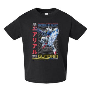 May include: A black short-sleeve t-shirt featuring a graphic of a white, blue, and red Gundam robot. The design includes a grid background, the text "MOBILE SUIT GUNDAM," "AD STELLA 122," "AERIAL XUX-816," and Japanese characters in red.