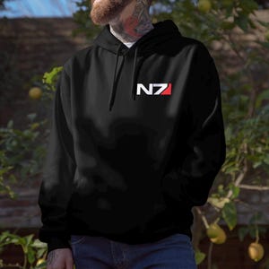 May include: Black hooded sweatshirt with the letters "N7" in white, with a red rectangle on the right side of the "N7" logo. The sweatshirt has a drawstring hood and a front pocket. The sweatshirt is made of a soft material.