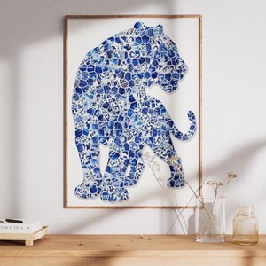 May include: A framed wall art print featuring a stylised tiger silhouette composed of a mosaic of blue and white porcelain-style floral and geometric patterns. The tiger is depicted in a standing profile view against a plain white background.