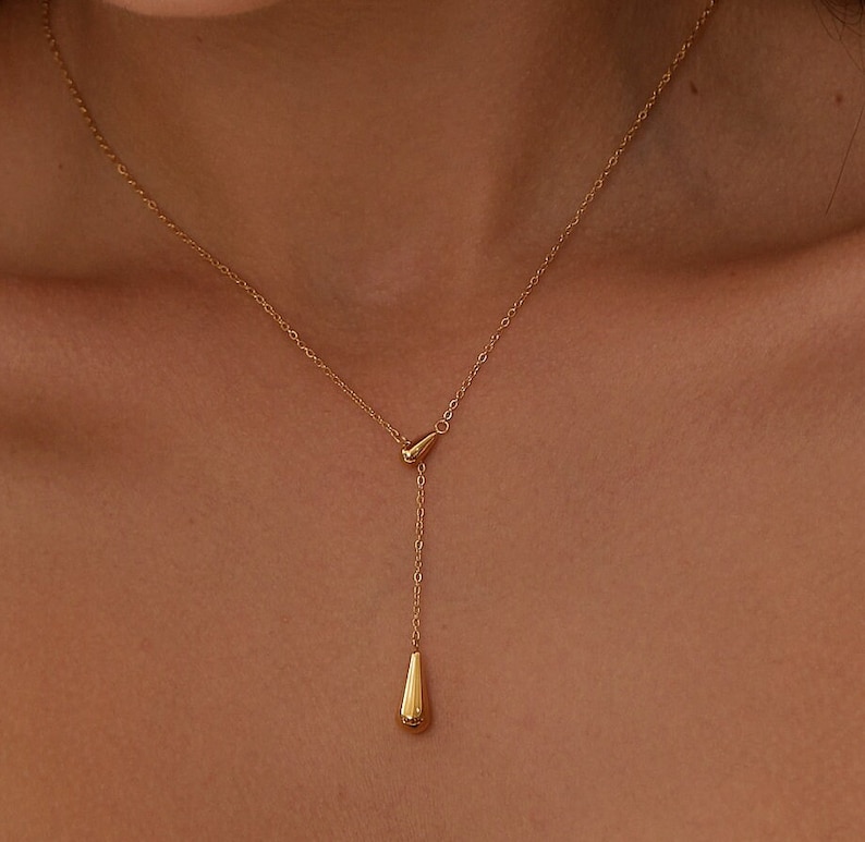 Puede incluir: Un collar de cadena dorada con un colgante en forma de l&aacute;grima. El collar es ajustable y se puede usar en diferentes longitudes.