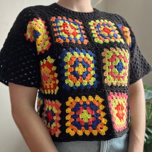 May include: A black crochet top with a colorful granny square pattern. The squares are made with orange, yellow, green, blue, and red yarn.