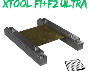 Puede incluir: Una mordaza de corte metálica para XTOOL F1+F2 ULTRA, con el texto "CUTTING VICE" en rojo y "XTOOL F1+F2 ULTRA" en verde. La mordaza sujeta una lámina de material color latón. También está presente el texto "ONLY COMPATIBLE WITH THE JIGMAKER".