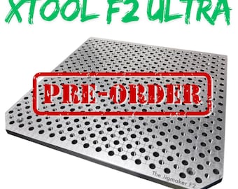 Puede incluir: Una placa de plantilla de acero plateado para el grabador láser XTool F2 Ultra, con numerosos agujeros pequeños. El texto "PRE-ORDER" está estampado en la placa. El texto superior dice "THE JIGMAKER STEEL FOR XTOOL F2 ULTRA", y el texto inferior dice "STEEL - USEABLE WITH MAGNETS".